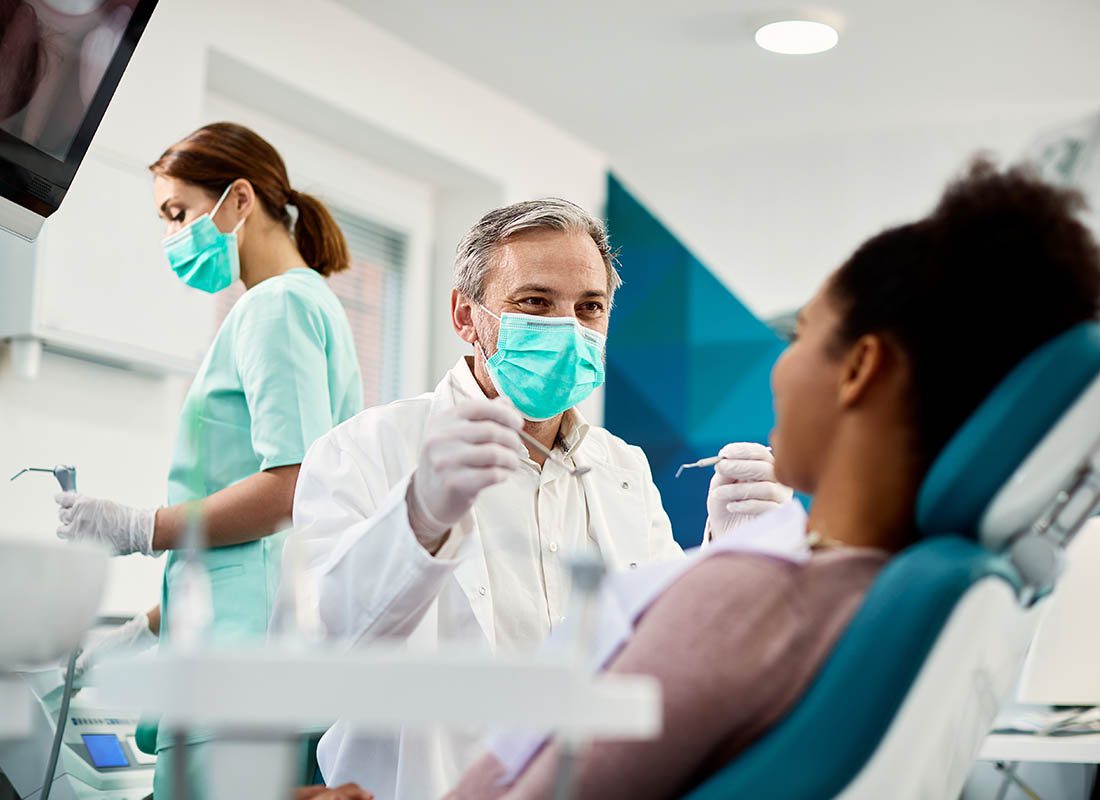 group dental insurance plans - Woman Getting Her Teeth Cleaned by a Dentist and an Assistant
