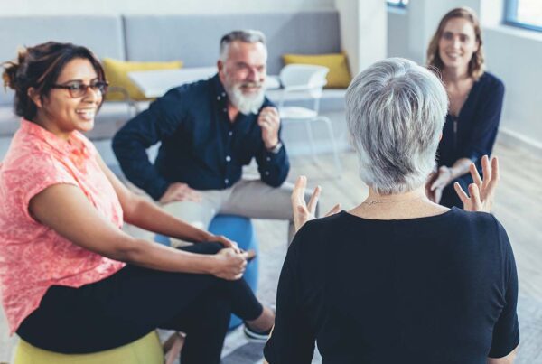 Employee Assistance Plan - Business Team Sitting in a Circle in a Large Office and Windows Discussing Employee Health and Well Being Support Tips